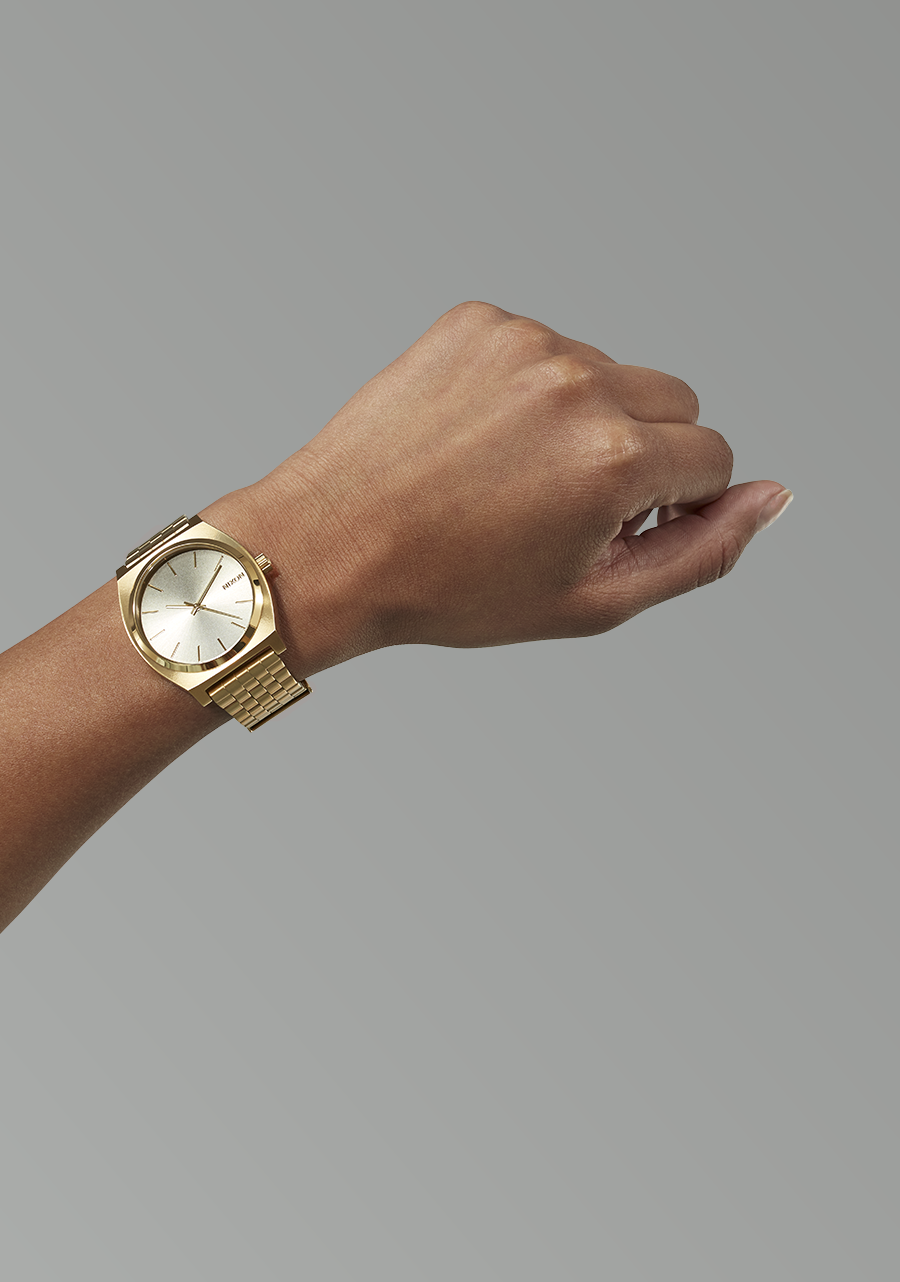 Gold wristwatch with a metallic band worn on a person’s wrist.
