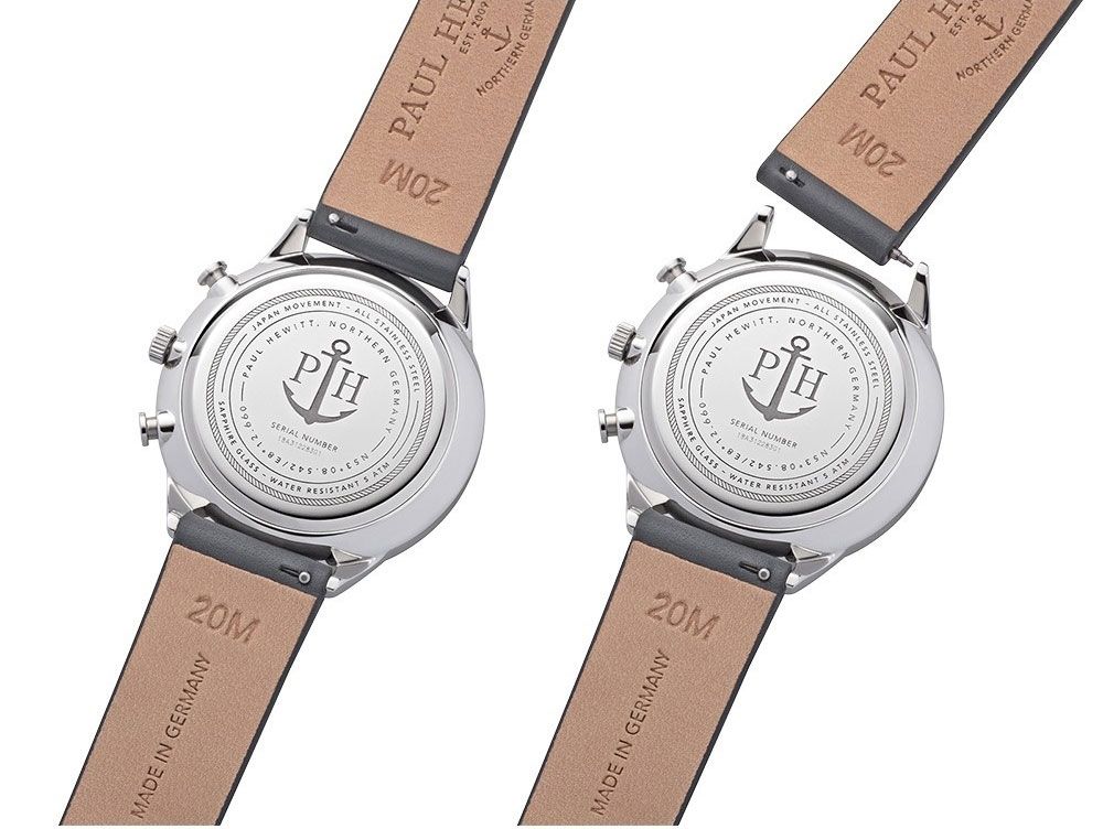 Two wristwatches with leather straps showing their casebacks, which feature an anchor logo.