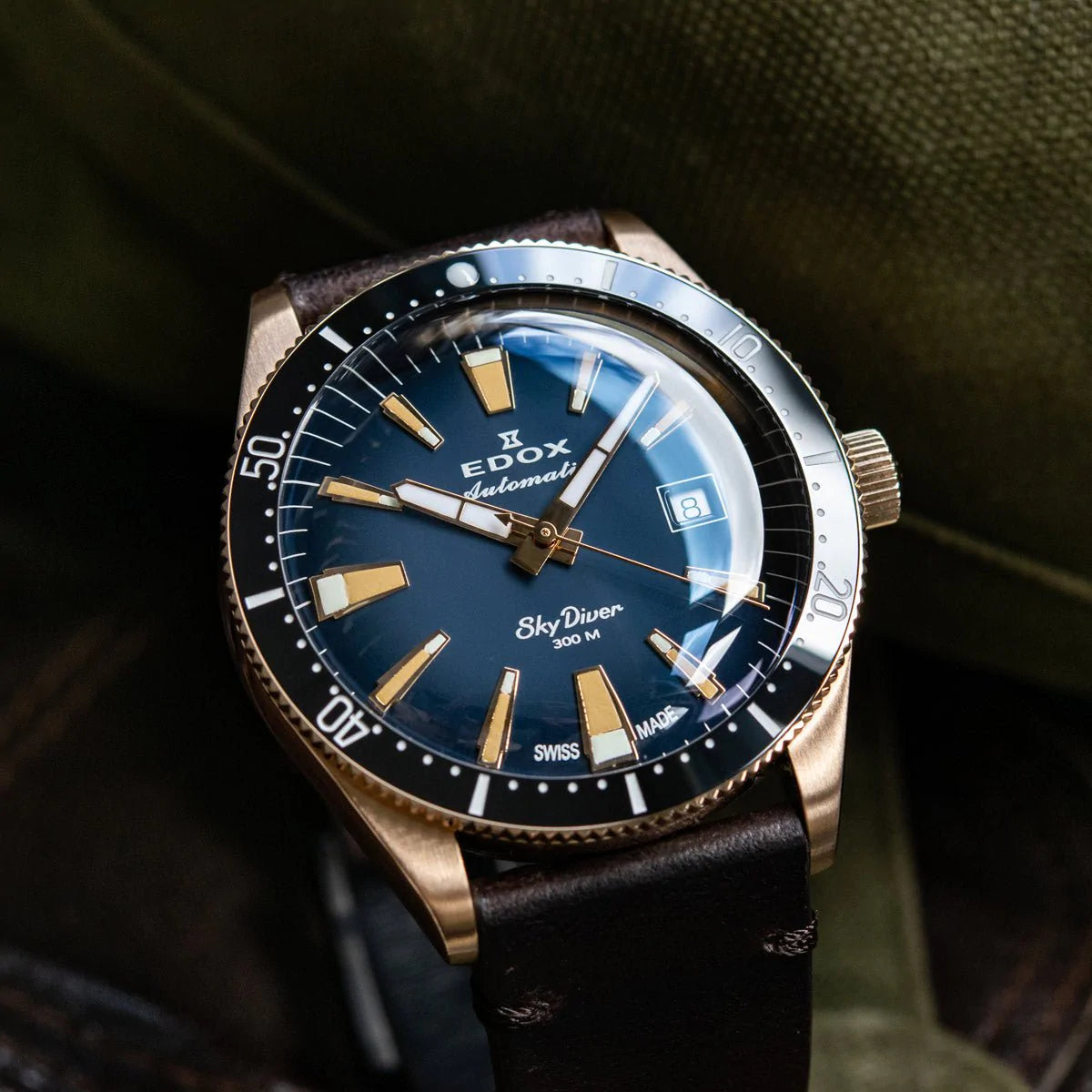 Luxury dive watch with a blue dial and gold-toned case on a leather strap.