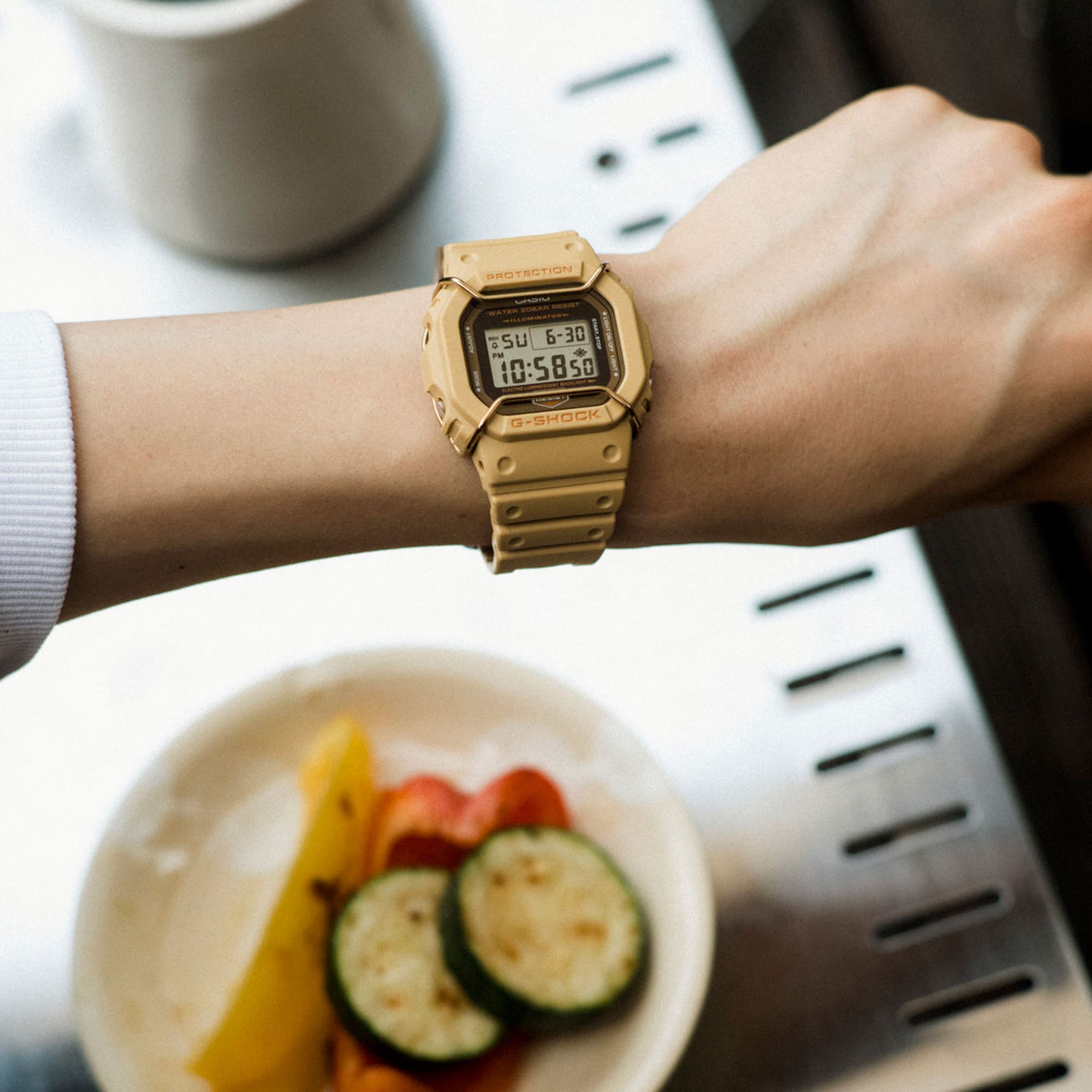 Gold-colored digital wristwatch with a square face.