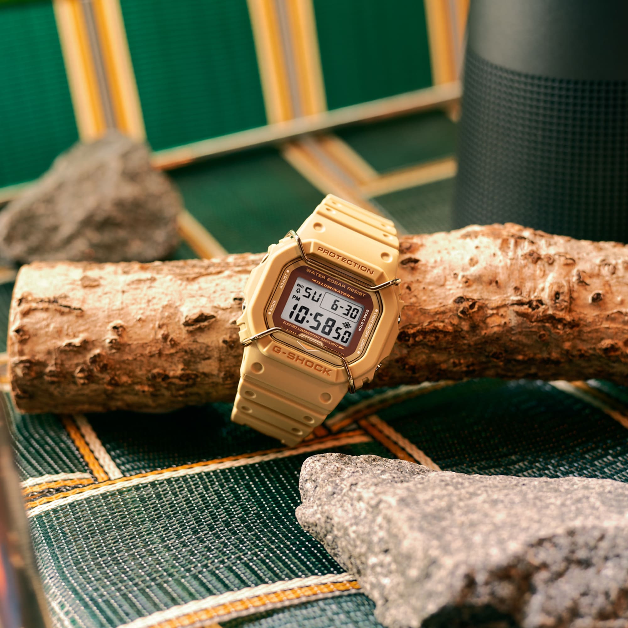 Gold-colored digital wristwatch with a square face resting on a log.