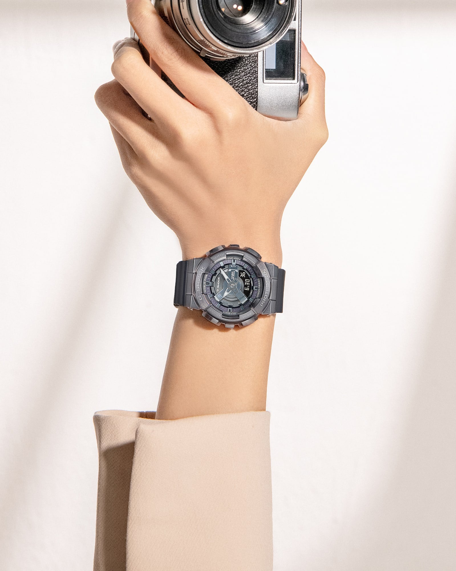 Hand holding a vintage camera while wearing a digital sports watch.