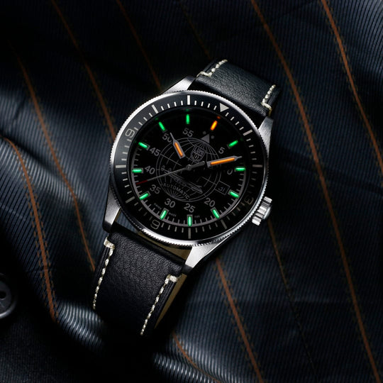 Sleek wristwatch with a black leather strap and luminous green hour markers on the dial.