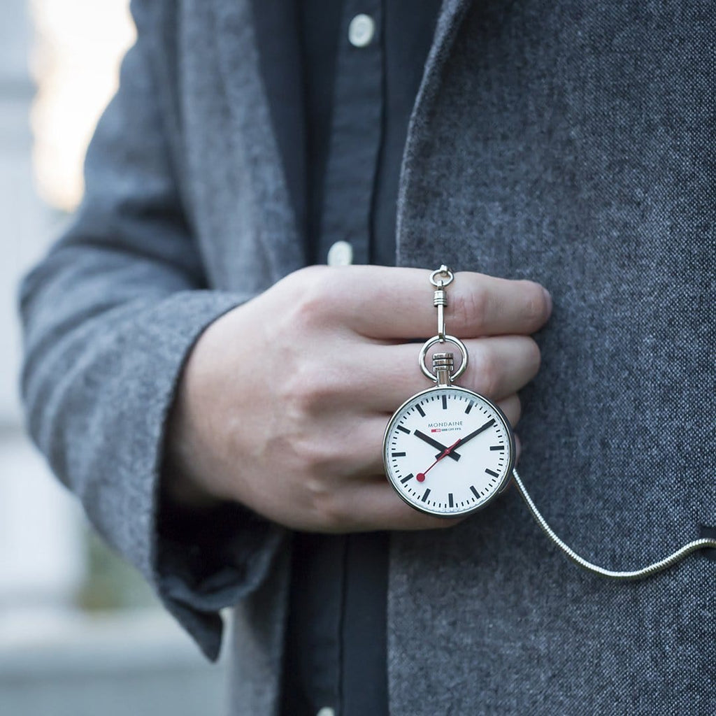 Pocket watch held by a hand wearing a ring.