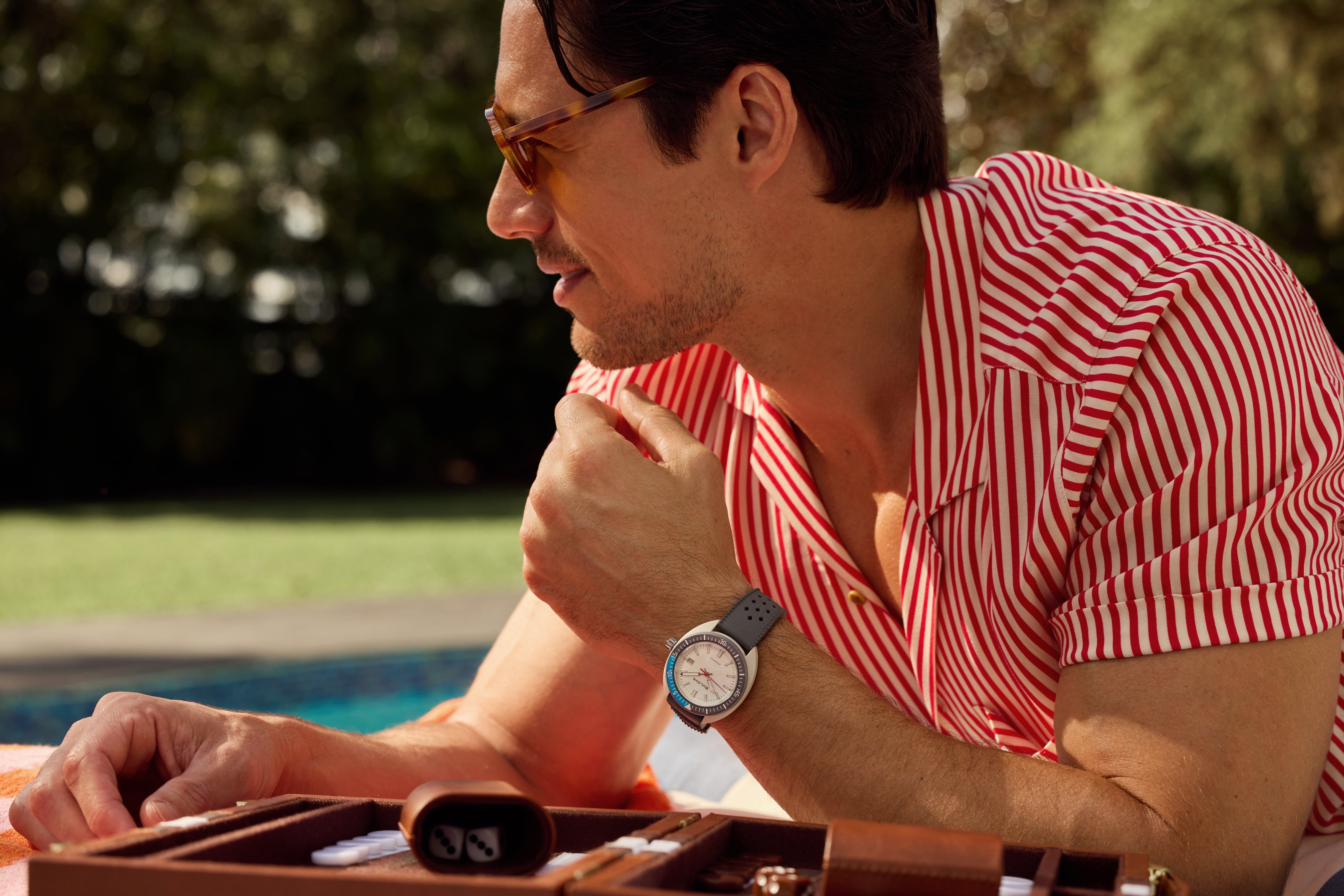 Man in a striped shirt wearing a Bulova Snorkel watch by the pool