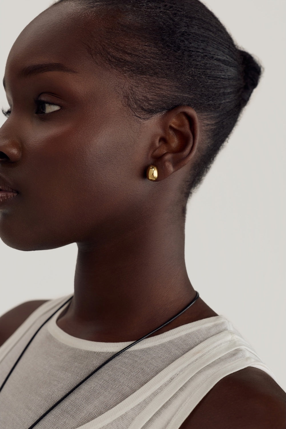 Cendré Bean gold earrings worn on the ear