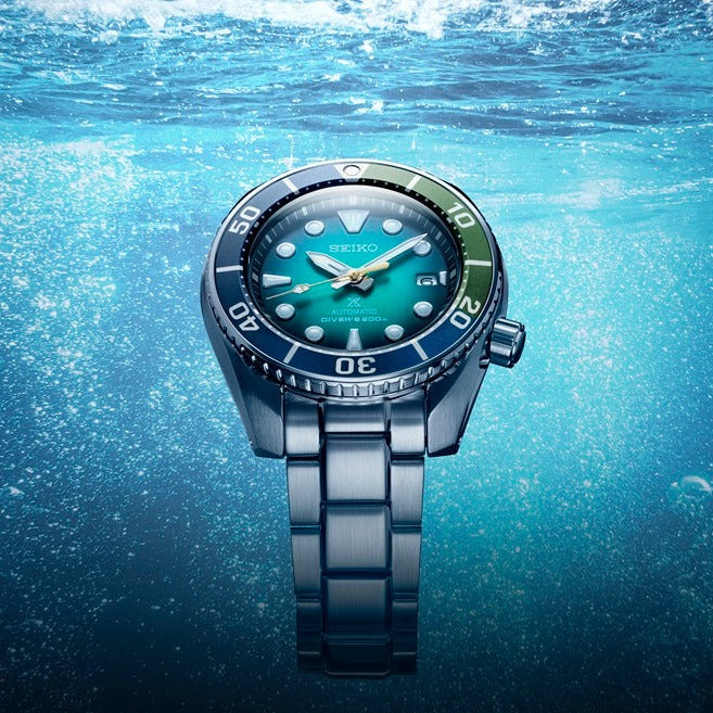 Stainless steel diving watch with a turquoise face underwater.