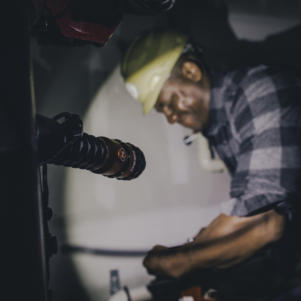 Man wearing a plaid shirt and hat speaking into a microphone.