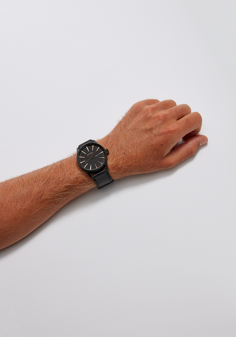 Wristwatch with a black face and band worn on a person’s arm.