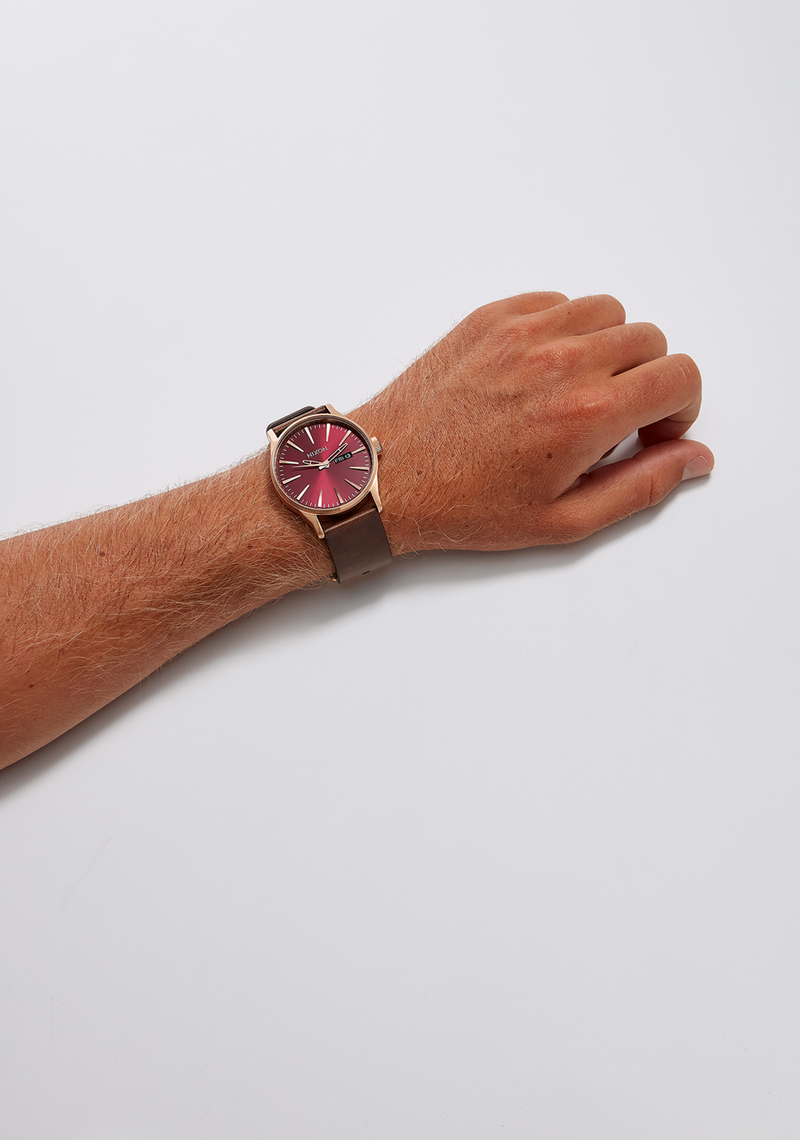 Wristwatch with a colorful red dial and brown leather strap.