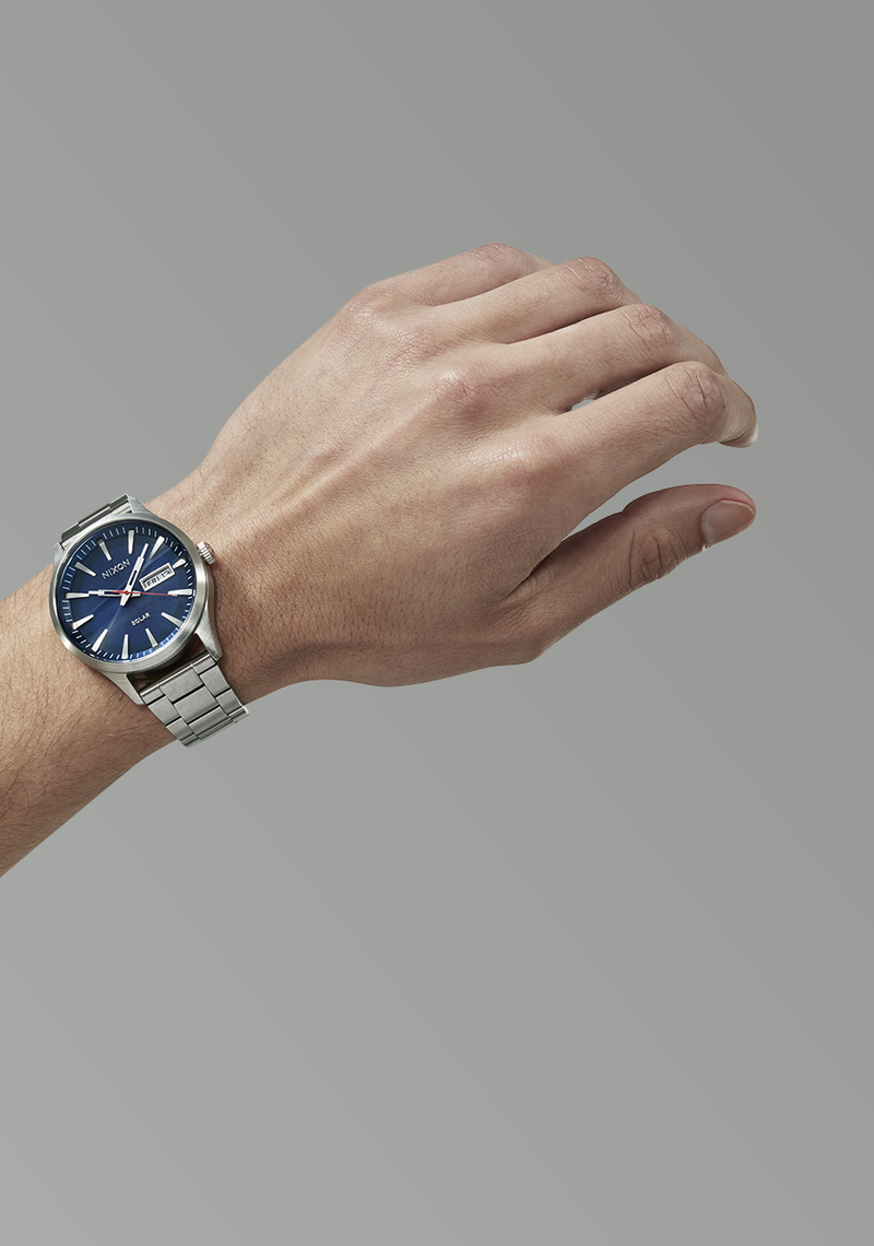 Wristwatch with a blue dial and metal bracelet worn on a person’s wrist.