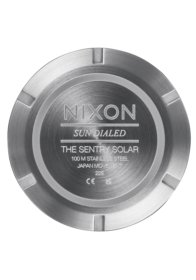 Circular metal watch case back with engraved Nixon branding and product details.