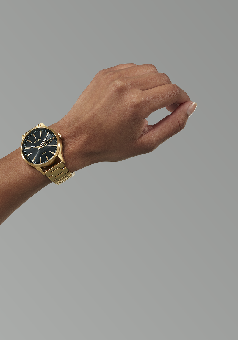 Gold wristwatch with a black dial and metal bracelet.