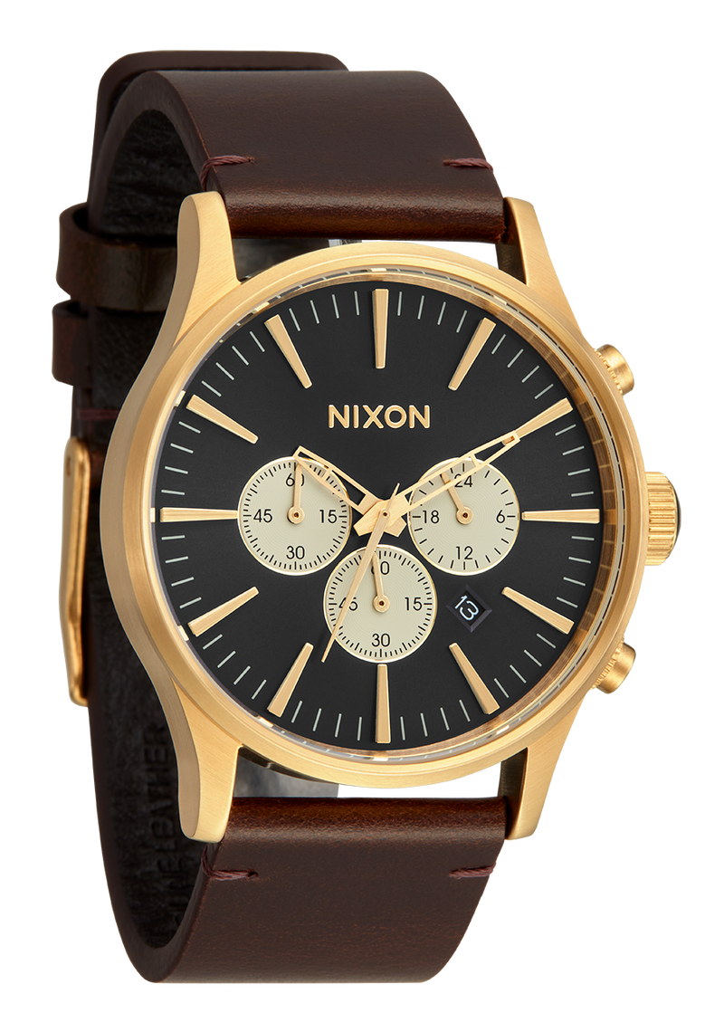 Gold-toned Nixon wristwatch with a black dial and brown leather strap.