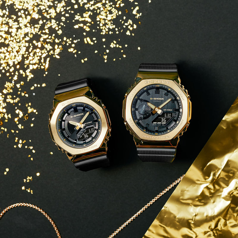 Two gold-toned luxury wristwatches with dark faces and metal bands.