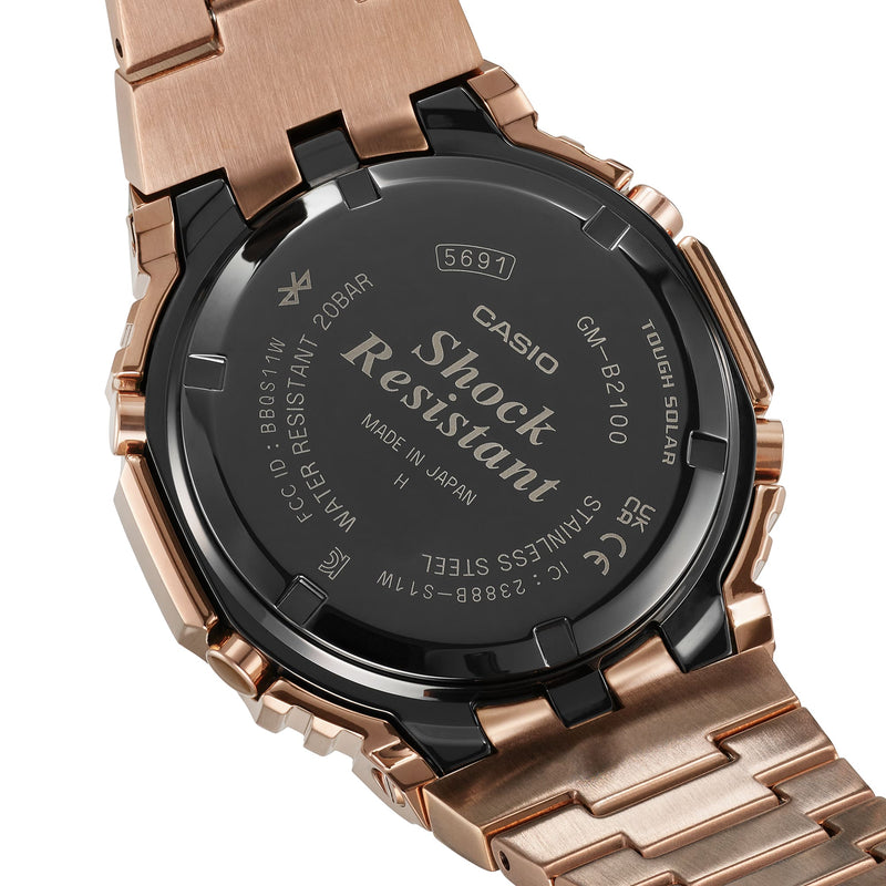 Rose gold-toned wristwatch with a black caseback displaying ’Shock Resistant’ text.