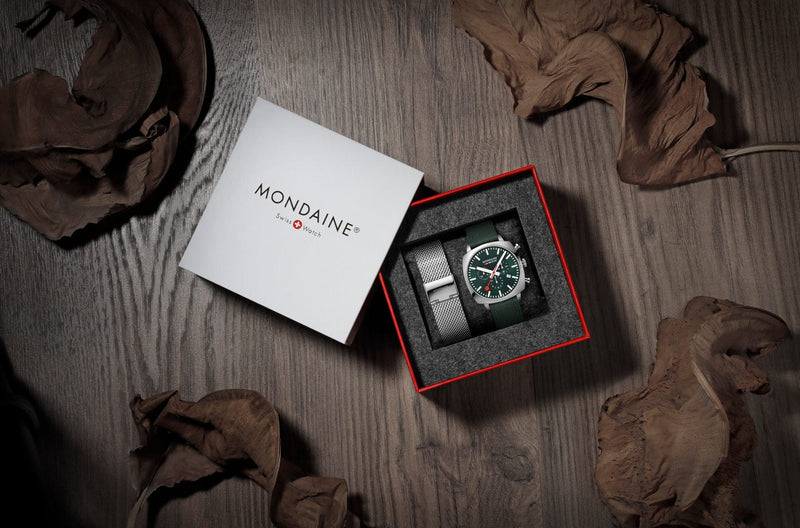 Wristwatch with a black face in an open Mondaine-branded box.