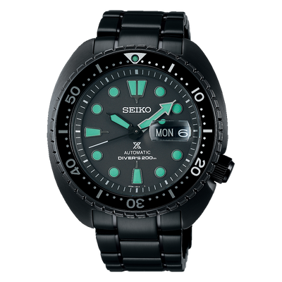 Black Seiko dive watch with turquoise hour markers and a day-date display.