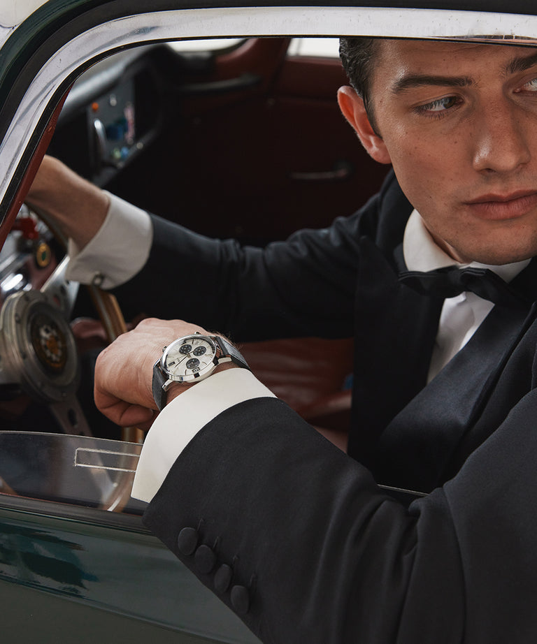 Luxury wristwatch with a distinctive patterned dial worn by a man in formal attire.