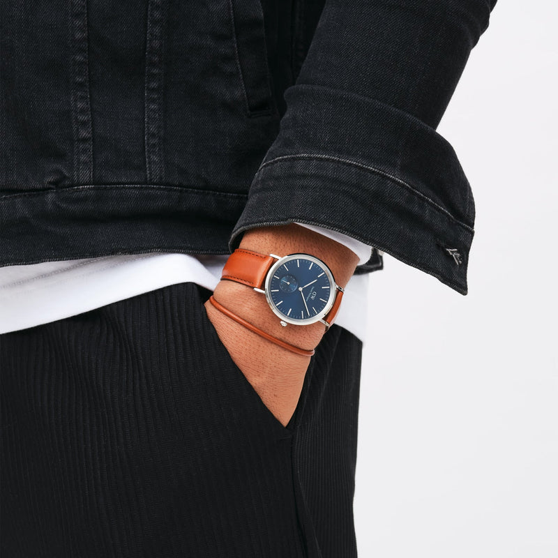 Wristwatch with a blue face and brown leather strap.