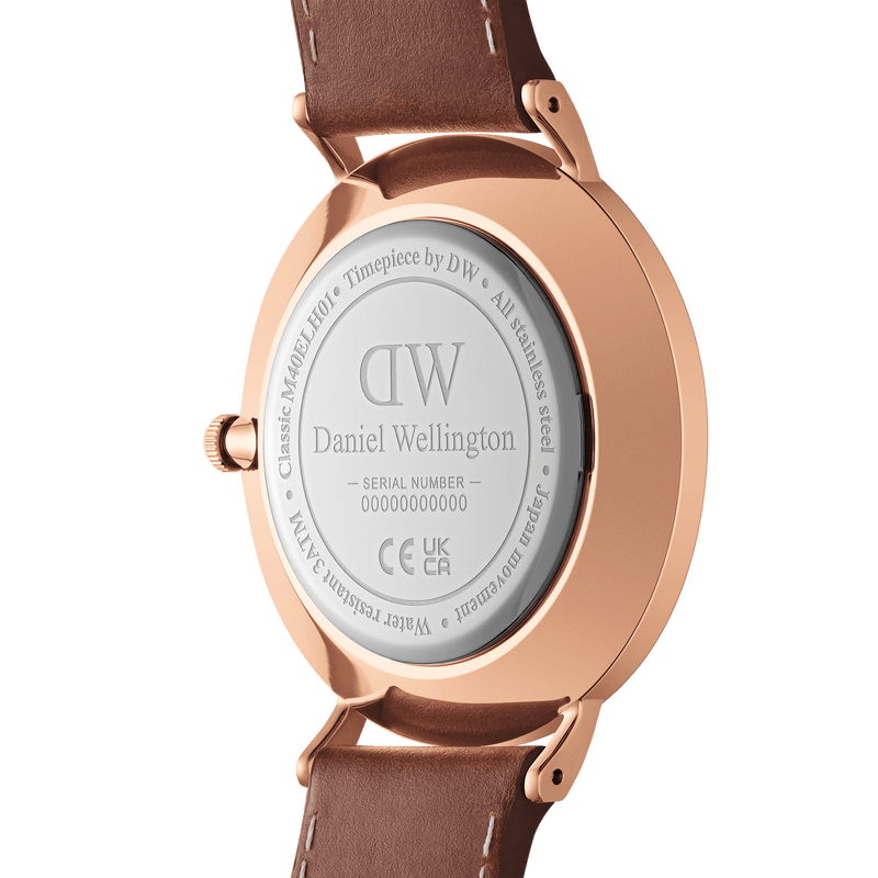 Back of a rose gold Daniel Wellington wristwatch with a brown leather strap.