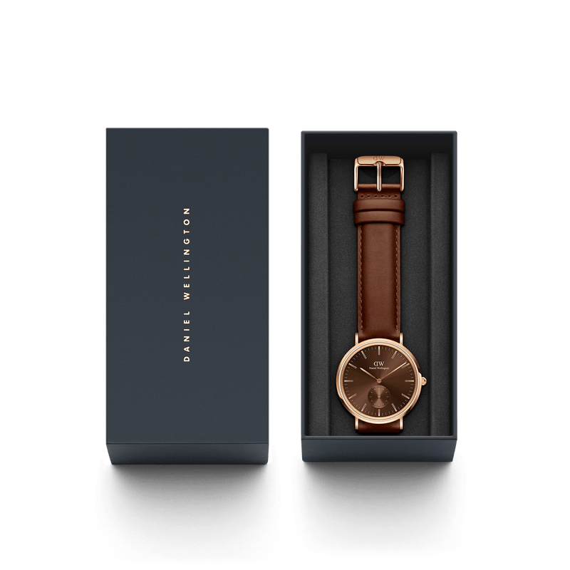 Wristwatch with a brown leather strap and rose gold-toned case in a presentation box.