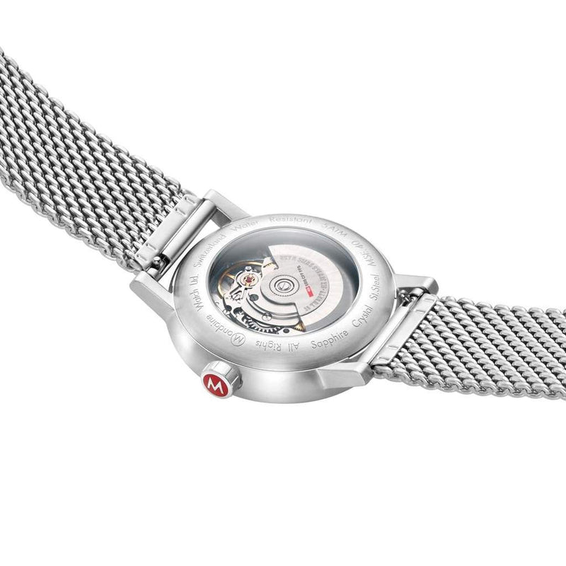 Stainless steel wristwatch with a mesh band and visible mechanical movement through the case back.