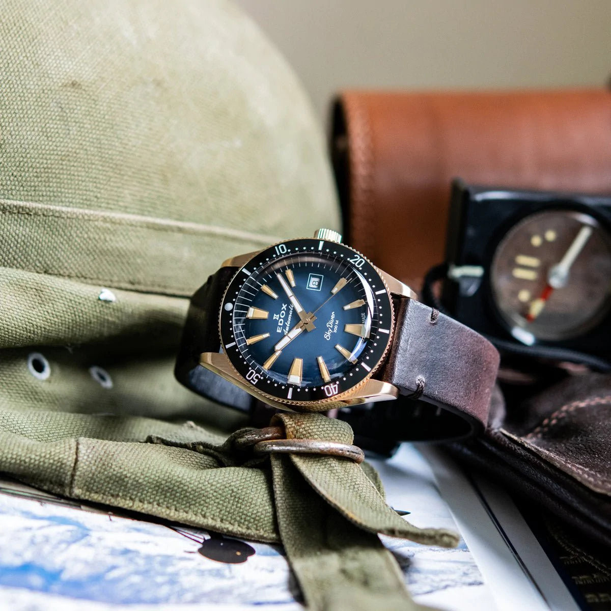 Wristwatch with a blue dial and black bezel on a gray leather strap.
