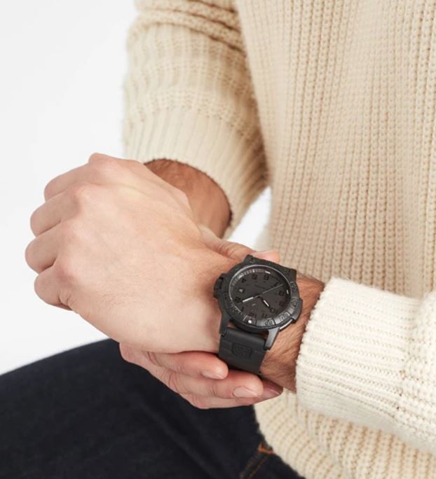 Wristwatch with a black face and dark strap worn on a person’s wrist.