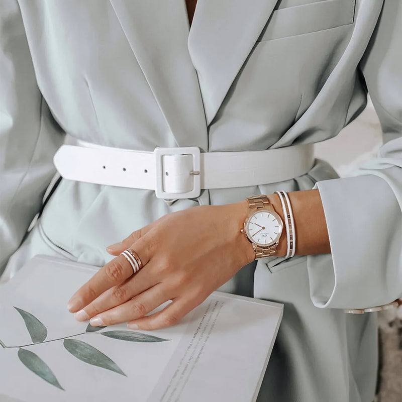 Light gray belted blazer or coat with a white watch and jewelry visible on the wearer’s wrist.