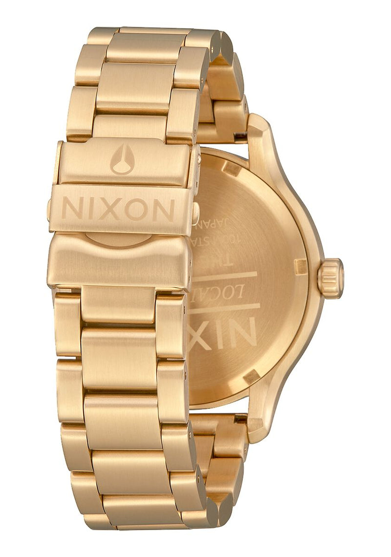 Gold-toned wristwatch with a metal link bracelet and Nixon branding.