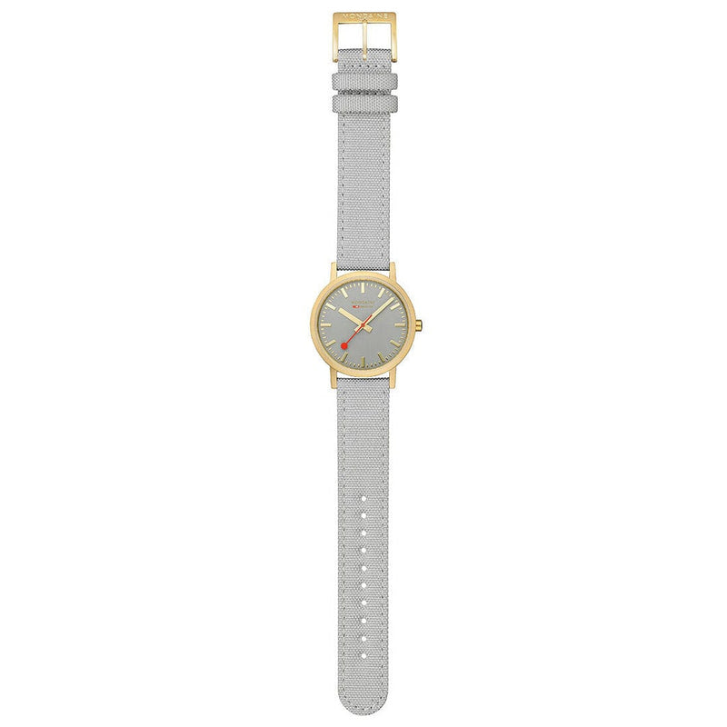 Wristwatch with a gold-tone case, gray dial, and light gray textile strap.