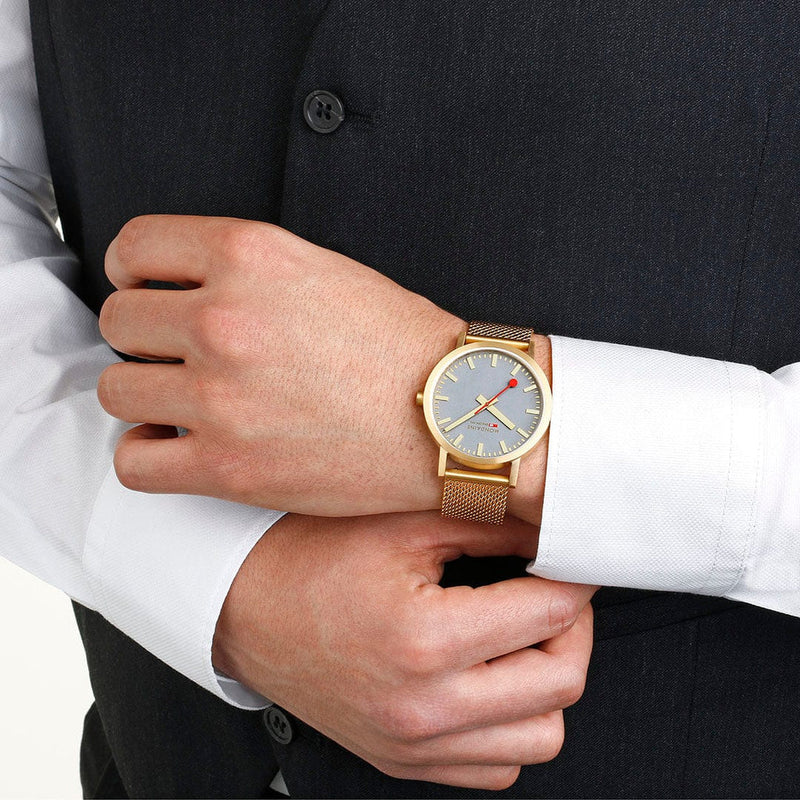 Gold wristwatch with a mesh band and gray dial.