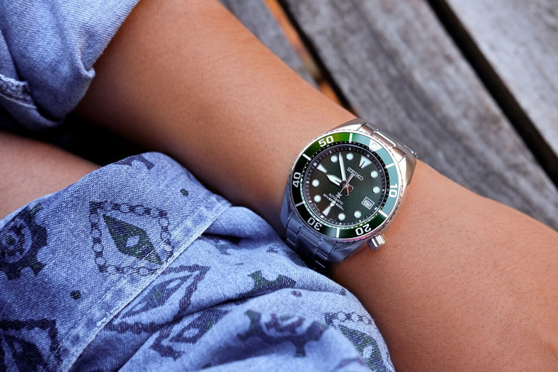 Green-dialed diving watch with a silver metal bracelet.