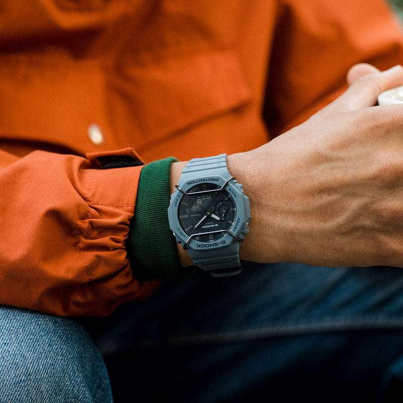 Digital wristwatch with a gray case and dark face worn on a wrist.