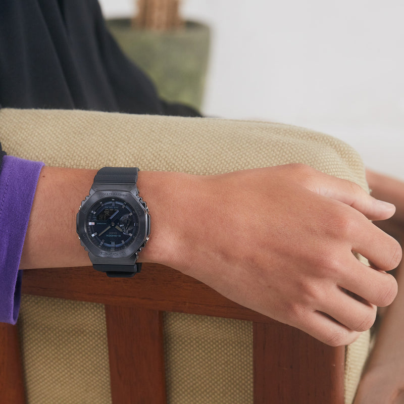 Dark gray digital wristwatch with a round face worn on a person’s wrist.