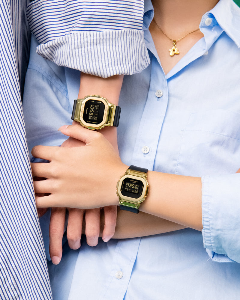 Gold digital watches worn on wrists.