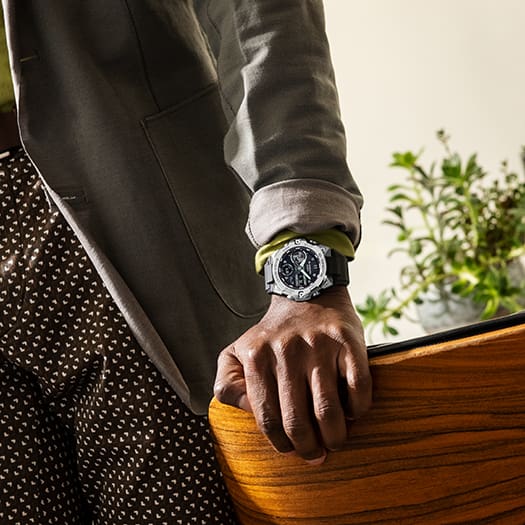 Wristwatch with a black face and silver bezel worn on a person’s wrist.