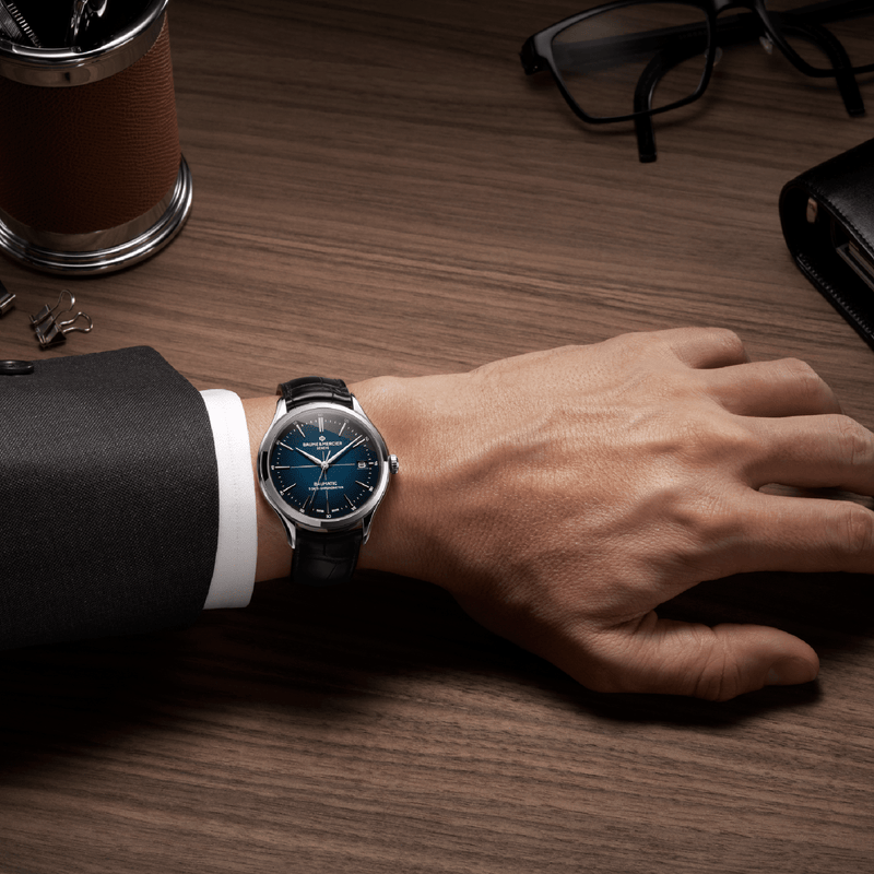 Elegant wristwatch with a blue dial and leather strap worn on a person’s wrist.