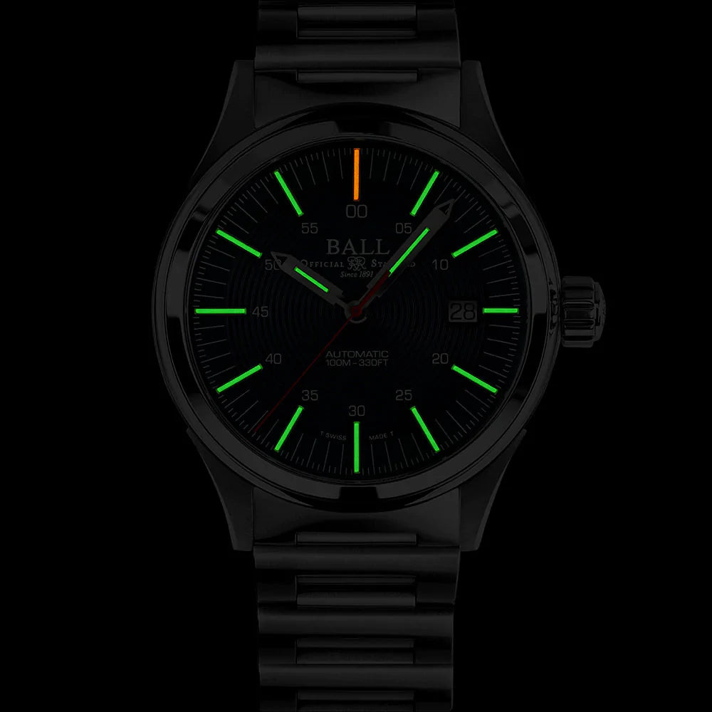 Wristwatch with glowing green hour markers and an orange second hand in a dark setting.