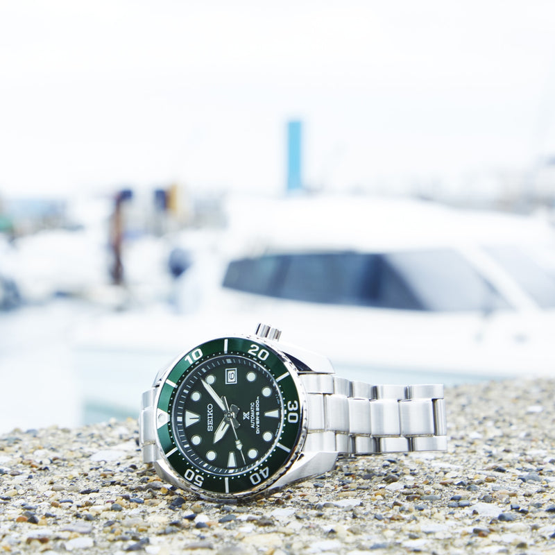 Stainless steel dive watch with a green bezel and black dial.