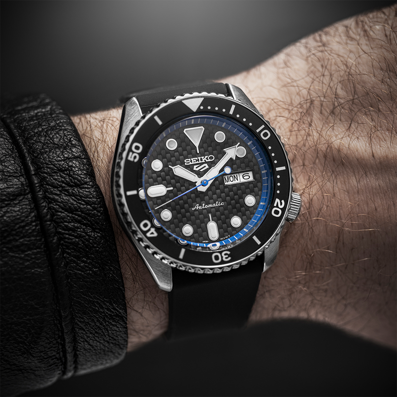 Seiko dive watch with a black dial and bezel worn on a wrist.