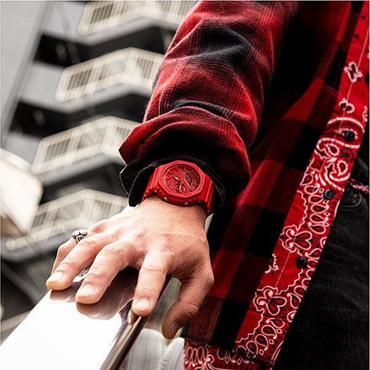 Red wristwatch worn on a person’s arm alongside a red patterned garment.