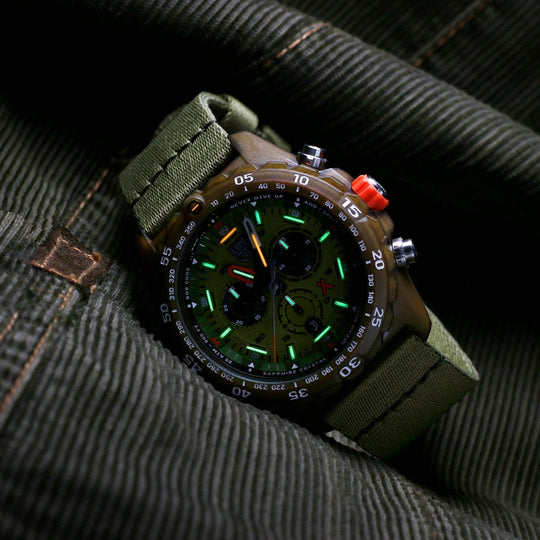 Military-style wristwatch with a green strap and illuminated dial.