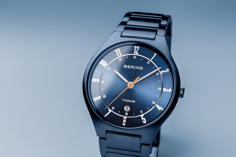 Blue wristwatch with a sleek metallic band and circular face displaying white numerals.