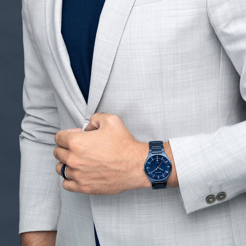 Blue-faced wristwatch with a matching blue metal band worn on a person’s wrist.