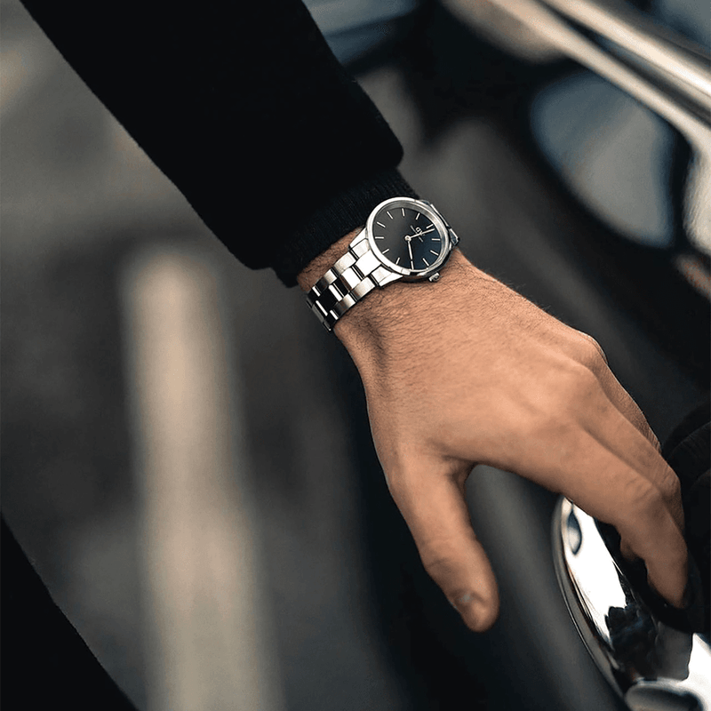 Elegant wristwatch with a silver metal band and black dial face.